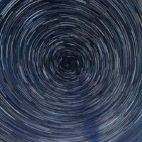 Person shining a light at the sky and making the stars rapidly move in circles - fantasy concept