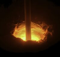 Close up of a hole in melting furnace with a rotating rod, metallurgical industry concept. Stock